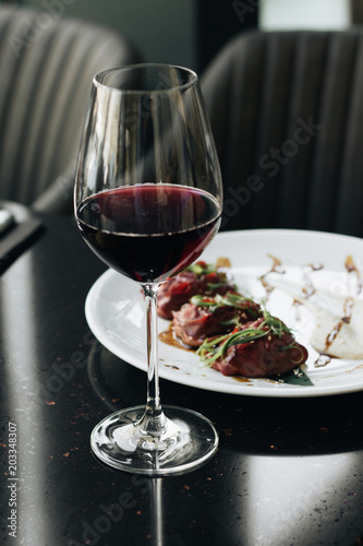 Wineglass with red wine and table with meal on black table