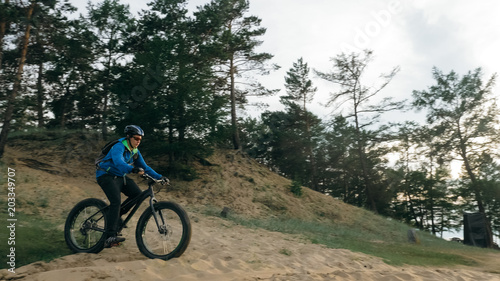 Fat bike also called fatbike or fat-tire bike in summer driving through the hills. The guy is riding a bike along the sand and grass high in the mountains. He performs some tricks and runs dangerously