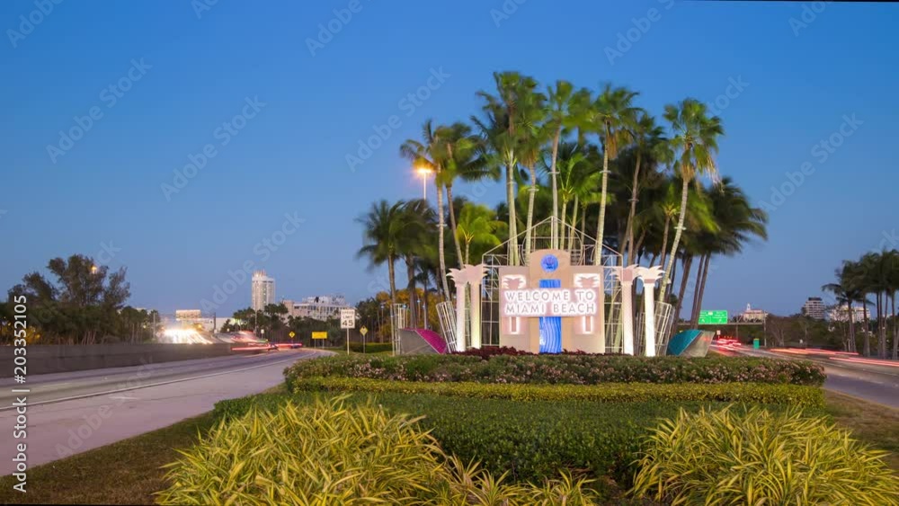 Welcome to Miami Beach FL Signage Traffic Timelapse with Moving Lights from Passing Cars in front of a Vibrant Blue South Florida Sky at Dusk