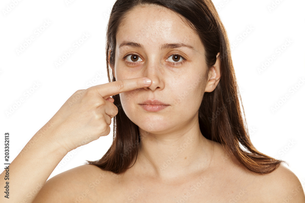 Beautiful young woman touching her nose on white background Beautiful young woman touching her nose on white background