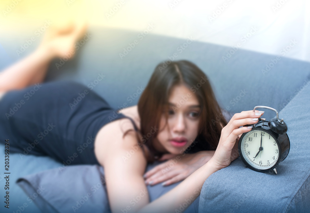 Pretty asian girl waking up with alarm clock (focus on the clock) Pretty asian girl waking up with alarm clock (focus on the clock)