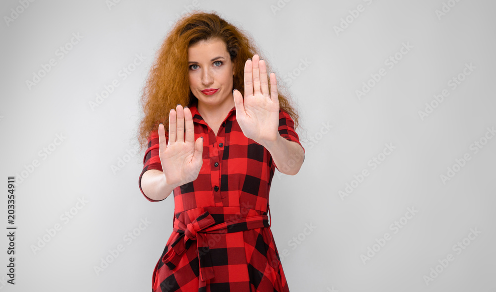 Portrait of beautiful redhead upset frustrated sad young woman showing stop sign on gray background Portrait of beautiful redhead upset frustrated sad young woman showing stop sign on gray background