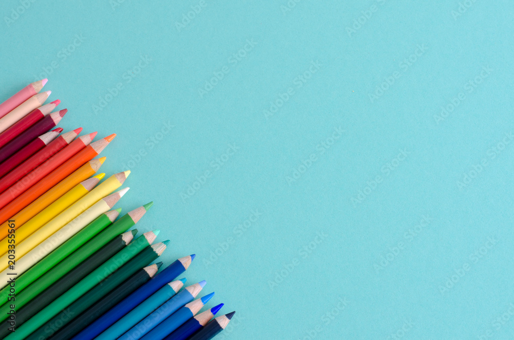 Fototapeta premium Colored pencils on blue background with space to write.