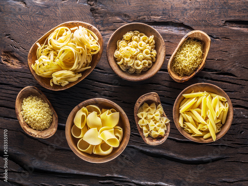 Different pasta types in wooden bowls on the table. Top view.