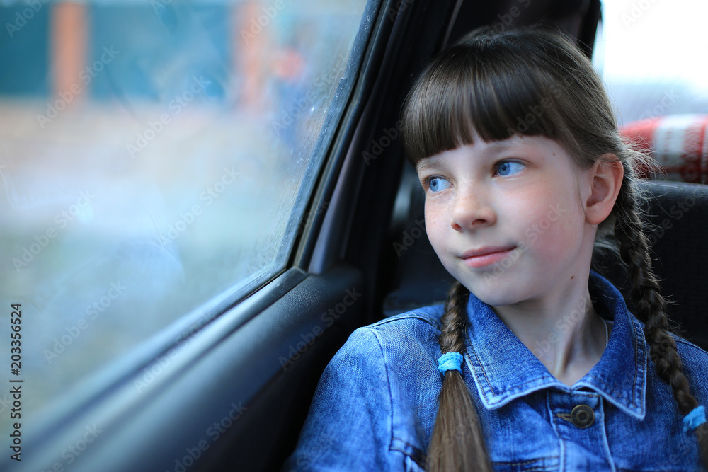little girl with blue eyes sitting in the back of the car at the window ...