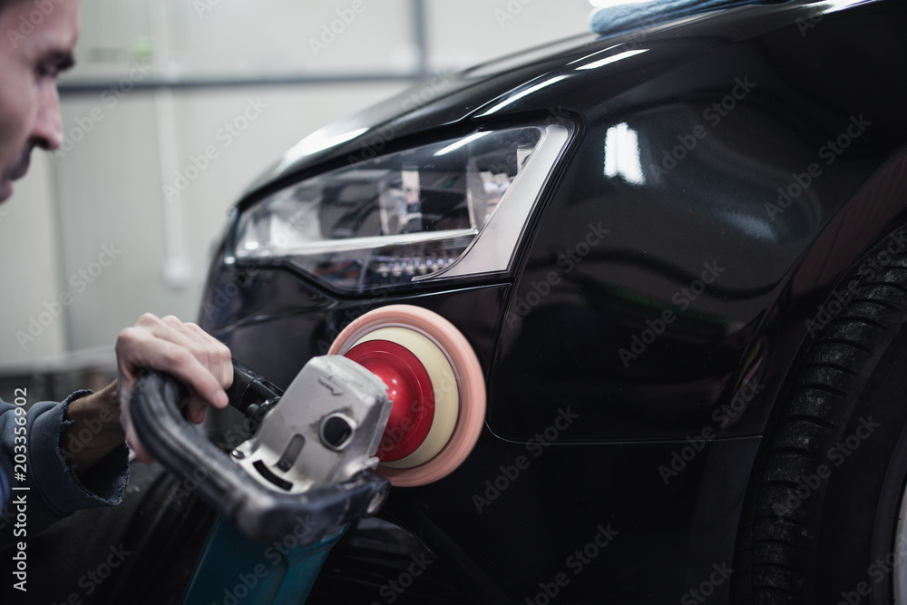Car detailing - Hands with orbital polisher in auto repair shop. Selective focus. Car detailing - Hands with orbital polisher in auto repair shop. Selective focus.