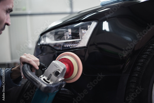 Car detailing - Hands with orbital polisher in auto repair shop. Selective focus. © Dusko