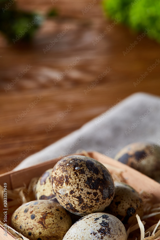 Quail eggs in the container over rustic wooden table, close-up, high angle view, selective focus.