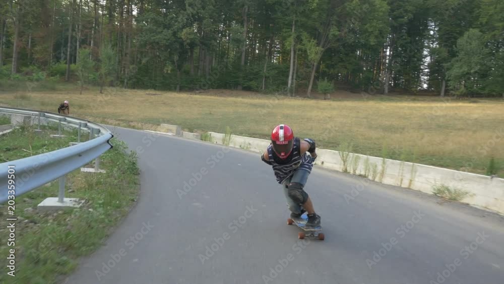 Longboarders passing by cars on a road Longboarders passing by cars on a road