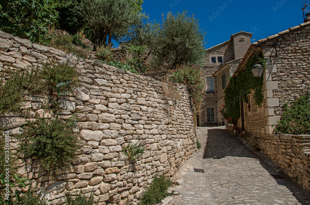 View of typical stone houses with sunny blue sky, in an alley of the historical city center of Gordes. Located in the Vaucluse department, Provence region, southeastern France