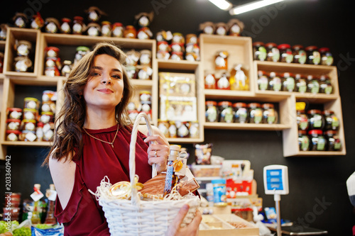 Girl in red holding different products on basket at deli store. photo
