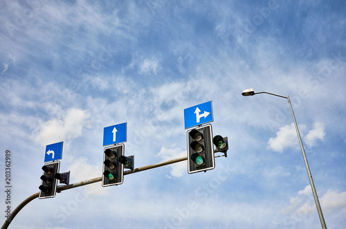 Traffic lights with countdown timers, green color displayed against the blue sky, space for text.