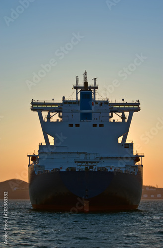 Rear view of a large LNG tanker standing in the roadstead at sunset.