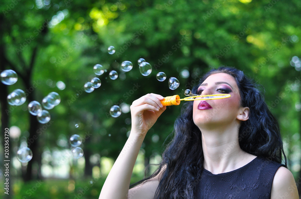Young beautiful woman blowing soap bubbles. Girl and soap bubbles in park Young beautiful woman blowing soap bubbles. Girl and soap bubbles in park