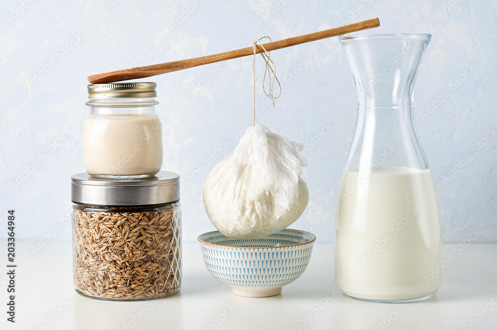 Preparation fresh cottage cheese. The curds in strainer to drain from a wooden spoon between two stacks of glass