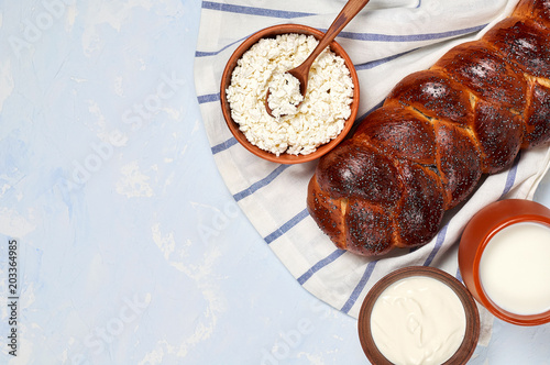 Challah bread with poppy seeds and set of dairy products comprising cottage cheese, sour cream and whole milk