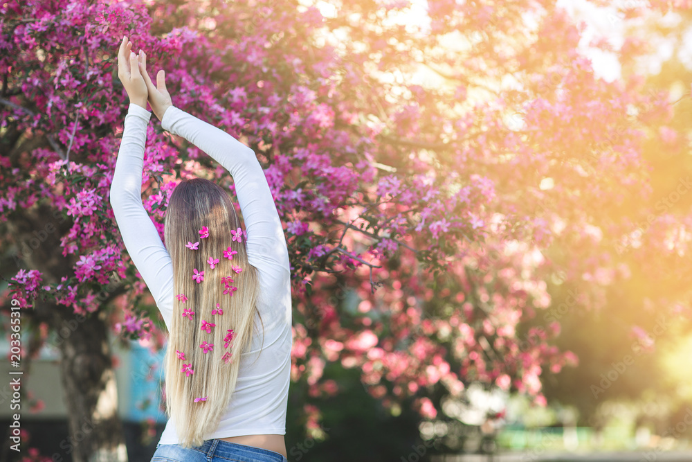 Young girl standing her back to the camera on the floral background ...