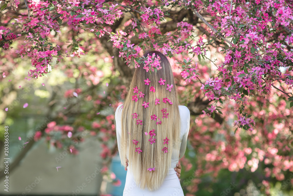Young girl standing her back to the camera on the floral background ...