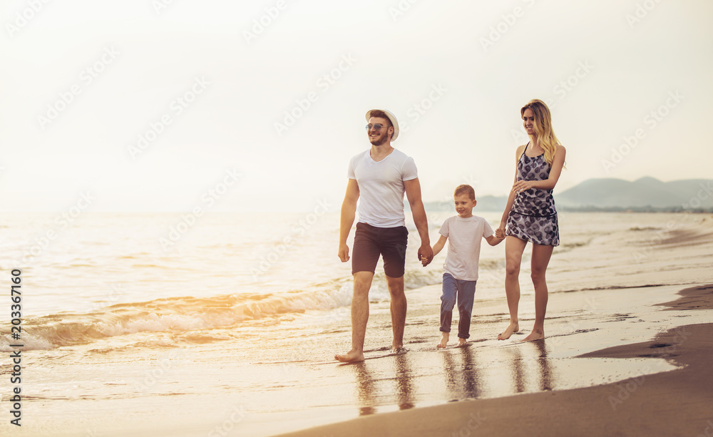 Mother and father with their son walking together on a quiet beach.