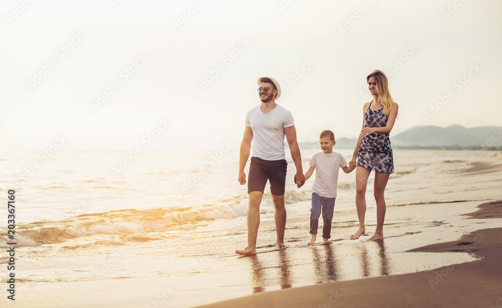 Mother and father with their son walking together on a quiet beach. Mother and father with their son walking together on a quiet beach.