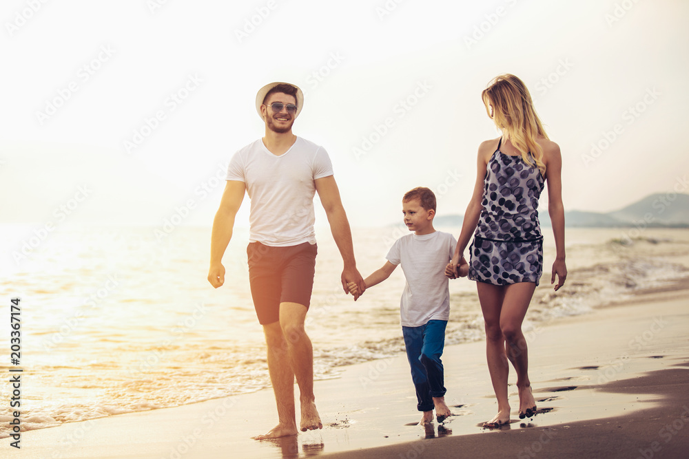 Mother and father with their son walking together on a quiet beach. Mother and father with their son walking together on a quiet beach.