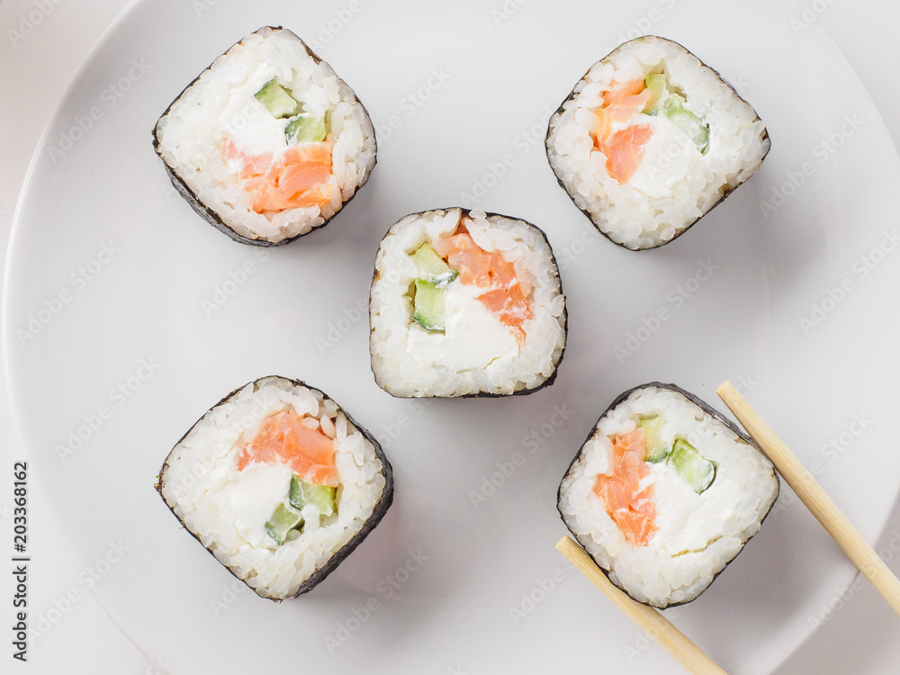 Japanese restaurant, sushi roll on white plate. Set for one person with chopsticks, ginger, soy, top view, copy space Japanese restaurant, sushi roll on white plate. Set for one person with chopsticks, ginger, soy, top view, copy space