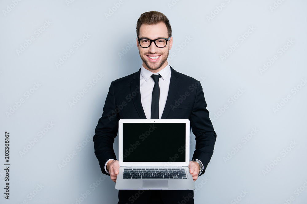 Portrait of cheerful confident handsome excited smart intelligent freelancer showing netbook with place for text on the empty monitor, isolated om gray background, copyspace Portrait of cheerful confident handsome excited smart intelligent freelancer showing netbook with place for text on the empty monitor, isolated om gray background, copyspace
