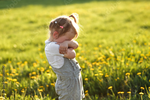 фотографія a young cule little girl hiding her face with her arms crossed