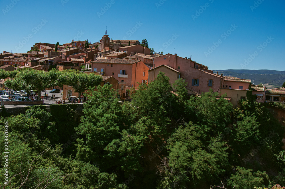 Panoramic view of the village of Roussillon and surrounding woods, under a sunny blue sky. Located in the Vaucluse department, Provence region, in southeastern France