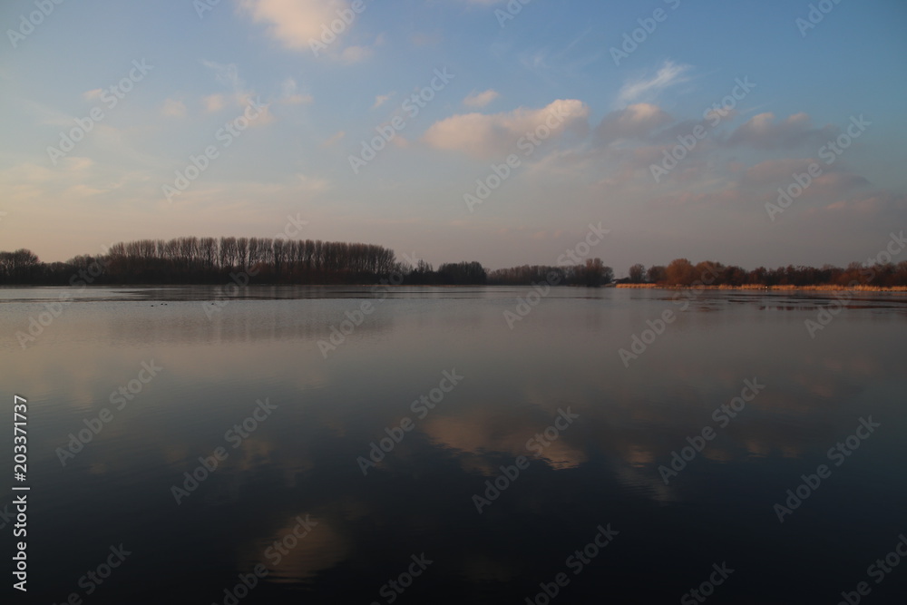 sunset over the river Rotte in Zevenhuizen near Rotterdam with reflection on the water and colored sky