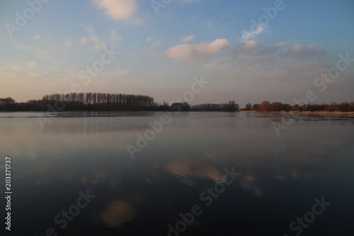 sunset over the river Rotte in Zevenhuizen near Rotterdam with reflection on the water and colored sky