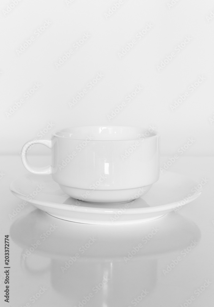 White coffee cup on a white plate on a white background.