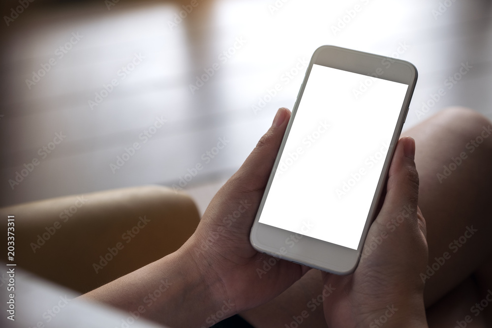 Mockup image of woman's hands holding white mobile phone with blank desktop screen sitting in cafe Mockup image of woman's hands holding white mobile phone with blank desktop screen sitting in cafe