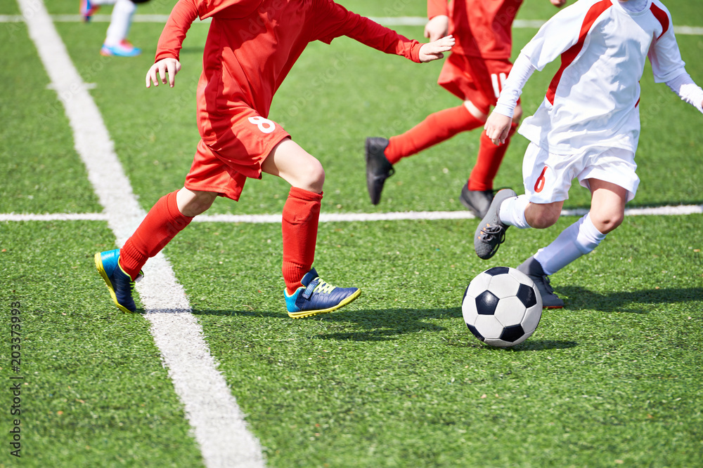 Child soccer players and ball on football field