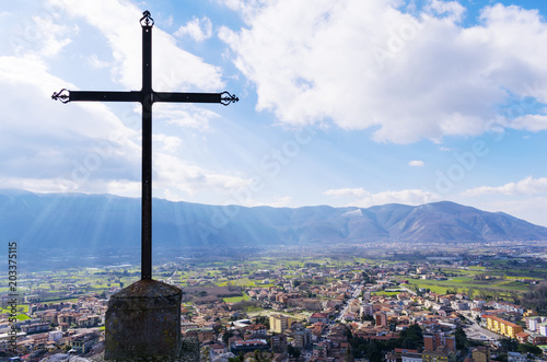 A steel Christian cross on top of a mountain and a city landscape. Beautiful cityscape. Italy photo