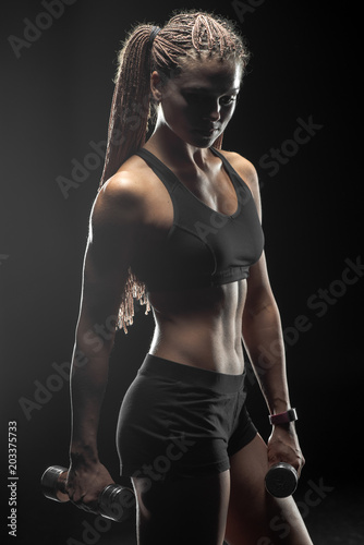 Beautiful sports fitness girl posing on black background