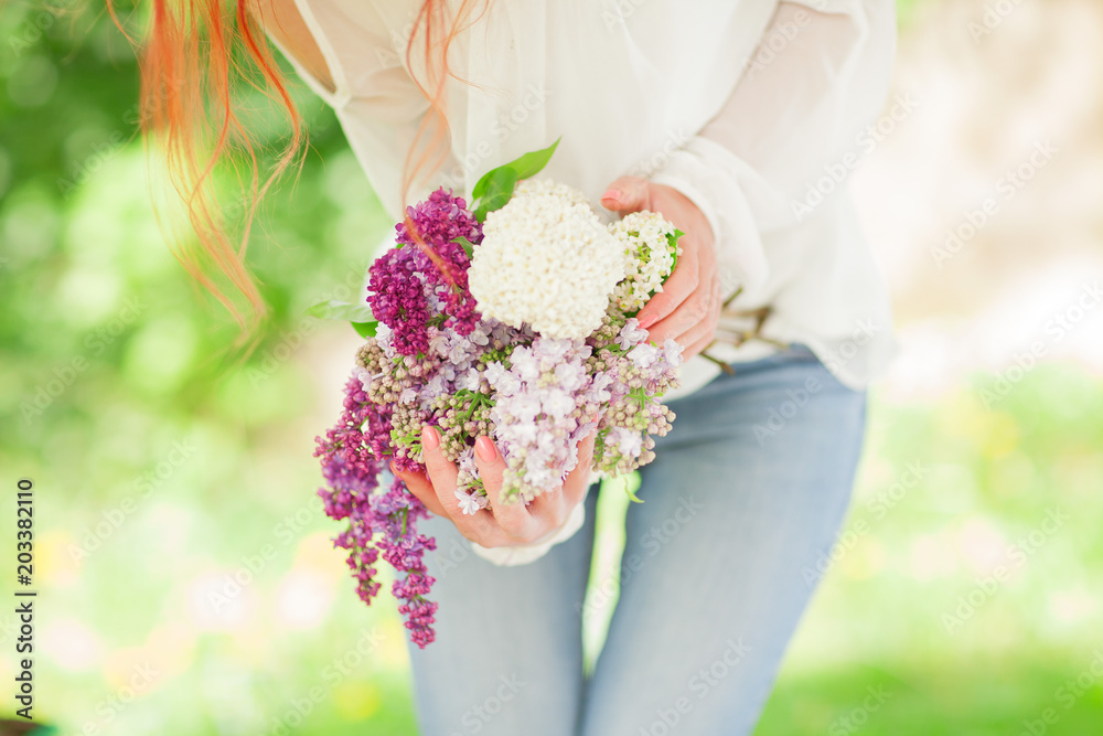 beautiful woman with red hair holding white and violet lilac bloom in her hands, outdoor garden, can be used as background beautiful woman with red hair holding white and violet lilac bloom in her hands, outdoor garden, can be used as background