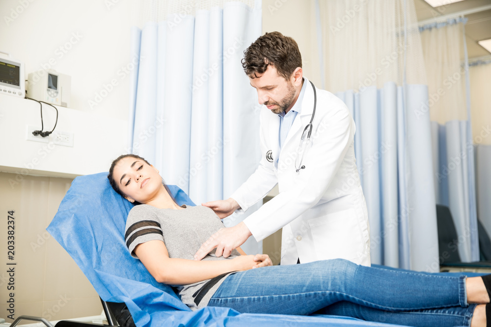 Fototapeta premium Doctor checking woman with stomach ache