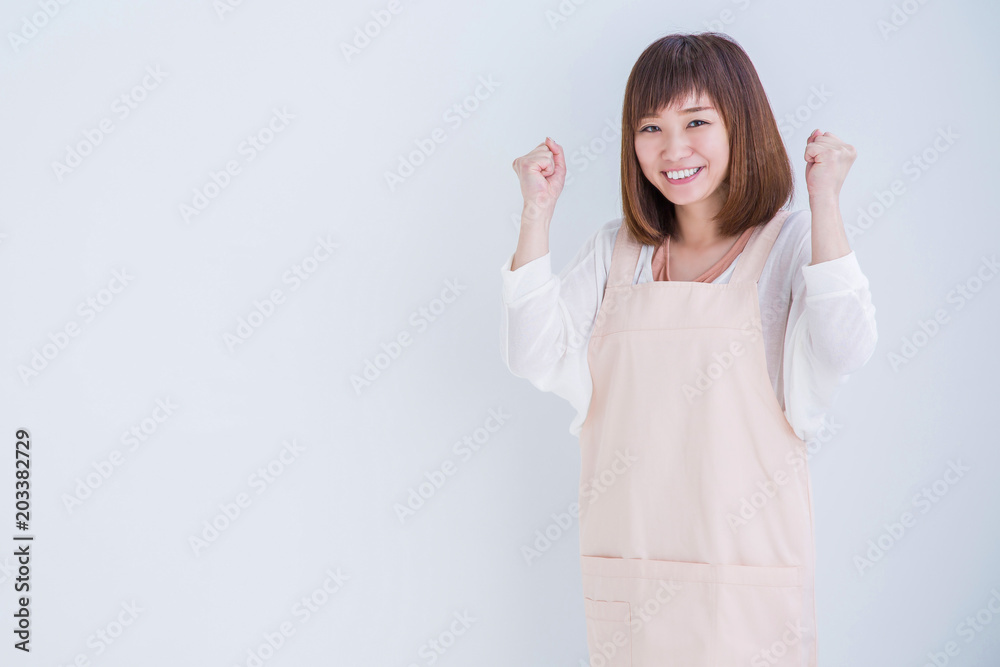 ガッツポーズするエプロン姿の女性
