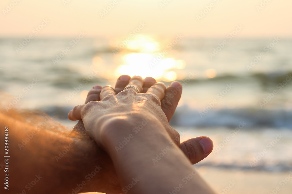 touch of male and female hands against the background of dawn at sea touch of male and female hands against the background of dawn at sea
