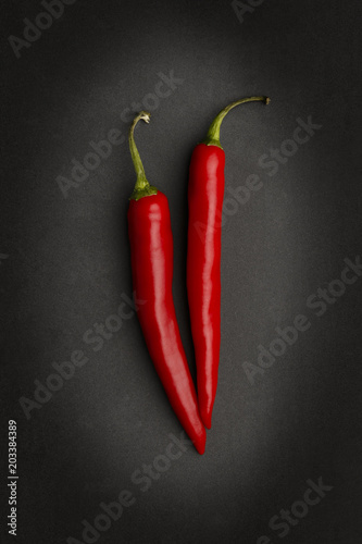 2 red chillies on a black background.