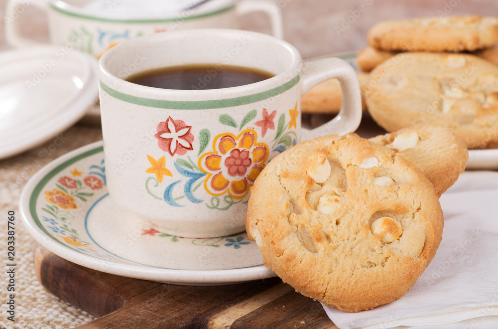 Closeup of white chocolate chip macadamia nut cookies and a cup of coffee Closeup of white chocolate chip macadamia nut cookies and a cup of coffee