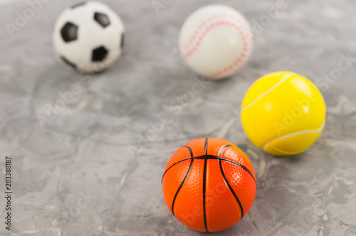 Four new soft rubber basketball and baseball and tennis and soccer balls on old worn cement