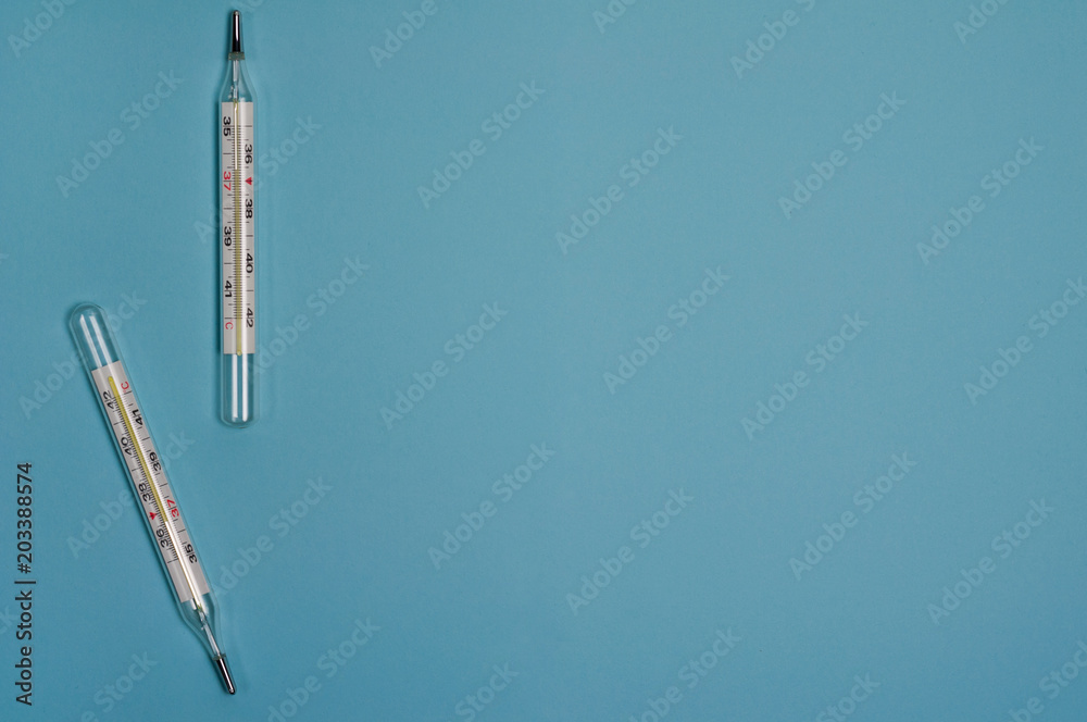 Two glass mercury thermometers on blue background. Top view with copy space Two glass mercury thermometers on blue background. Top view with copy space