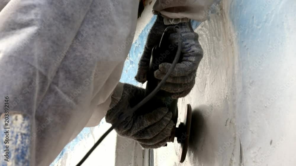 Working people tear off paint on metal in repairs process at shipyard. Workers in overalls reconstruct at ship repair yard outdoors in port. Working people tear off paint on metal in repairs process at shipyard. Workers in overalls reconstruct at ship repair yard outdoors in port.