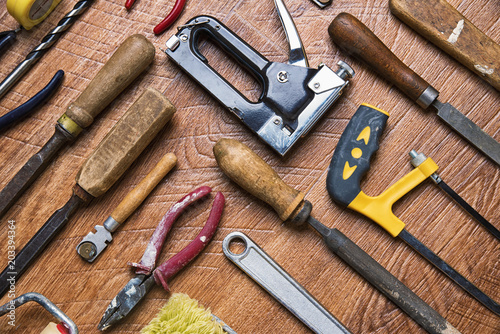 Tools with wooden handles for repair: chisels, pliers, stapler on a wooden background