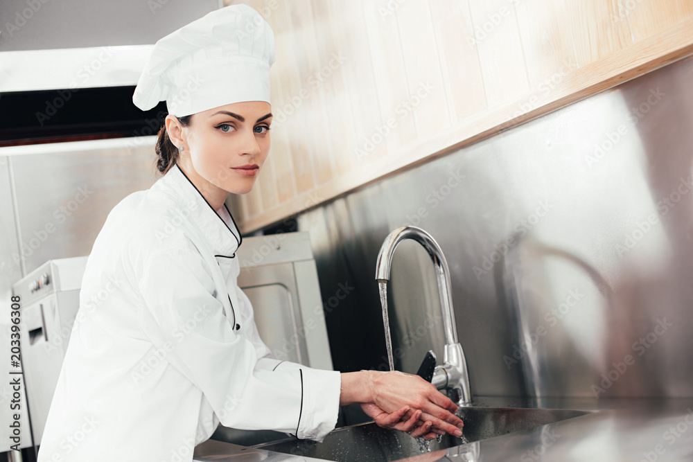 Female chef washing hands over kitchen sink