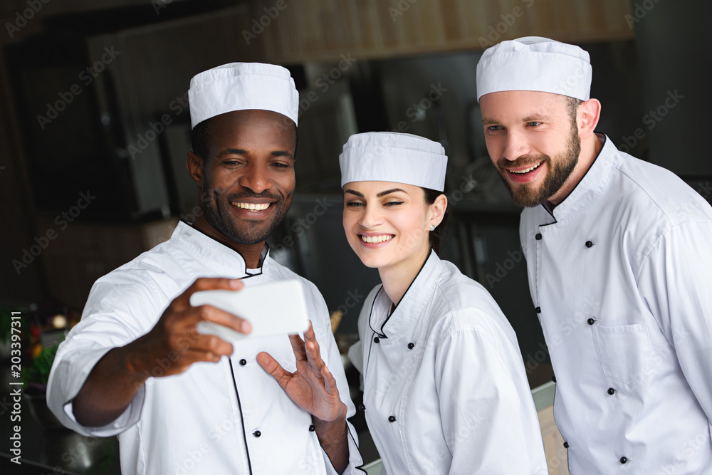 multicultural chefs taking selfie with smartphone at restaurant kitchen