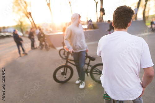 Abstract, blurry picture bmx riders at skate park at sunset background. Background with cyclists on bmx