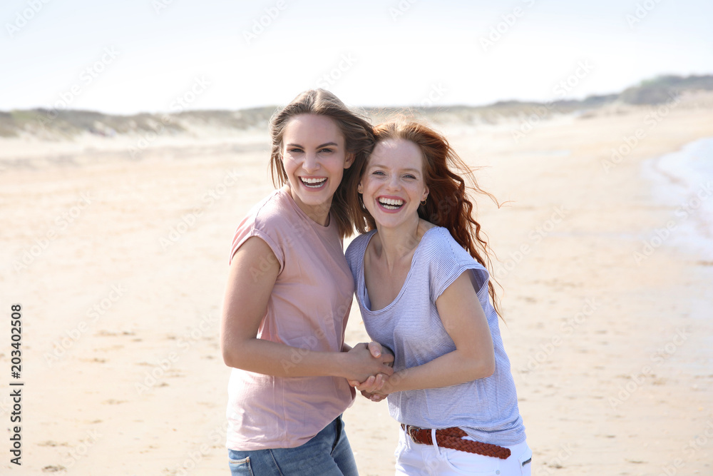 Zwei hübsche Frauen an einem Strand lachen